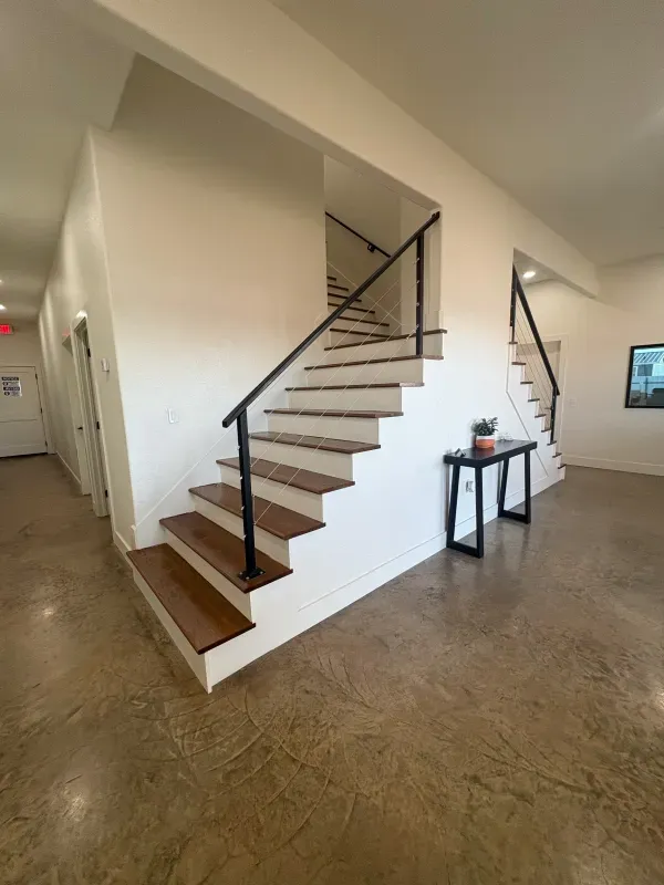 Staircase with wooden steps, black handrails, and a small table.