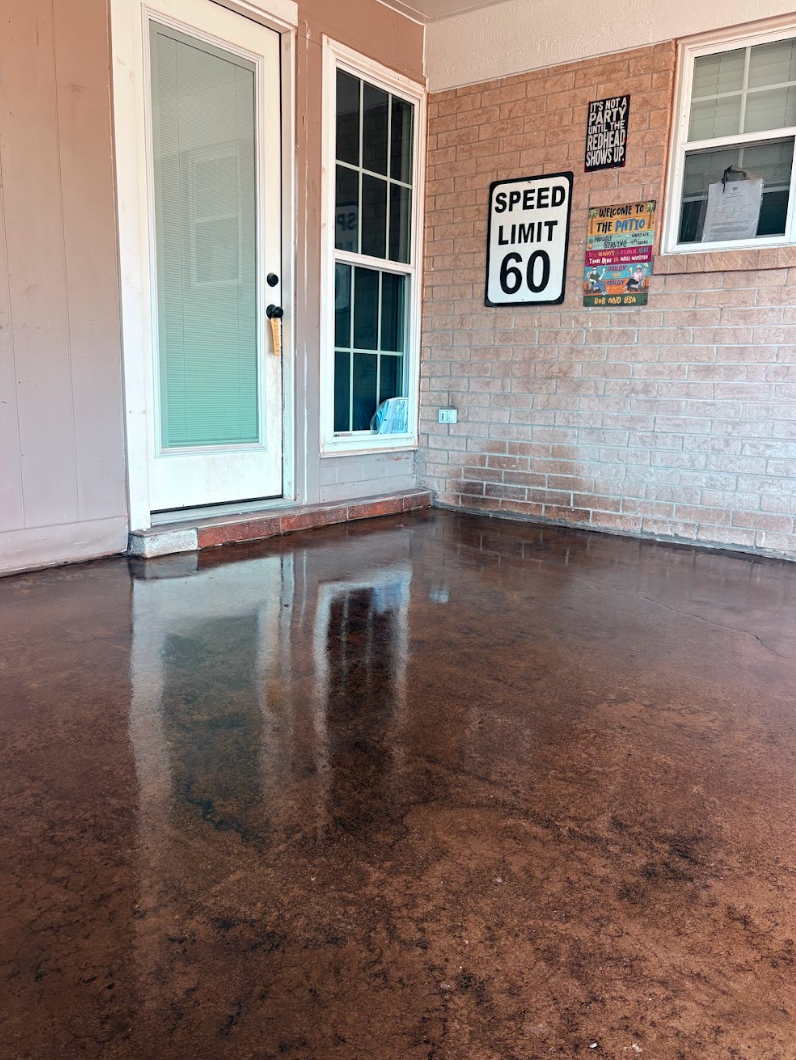 A porch with high-gloss, mottled reddish-brown concrete flooring, a white door, a window, and wall-mounted signage.