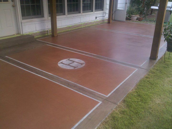 Pool area with a brick patio, brown fencing, and trees under a clear blue sky.