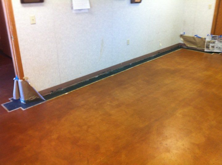 Spacious living area with brown shutters, dark ceiling fans, and a reflective epoxy floor.