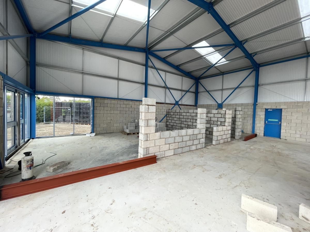 Interior of a warehouse under construction, with gray cinder block walls and a blue metal frame.