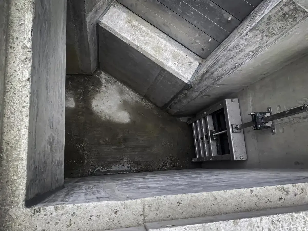 Concrete structure with a gate and a chain. Grey tones with wet patches.