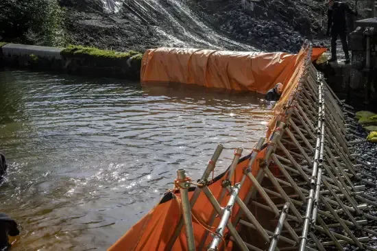 Orange barrier in a waterway, possibly for flood control or construction.