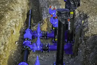 Blue water pipes and valves in a trench. Black pipes, metallic fittings.