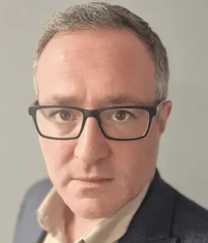 Man with graying hair wearing glasses and a blazer, looking directly at the camera.