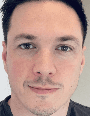 Man with dark hair and brown eyes, looking directly at the viewer, slight smile.