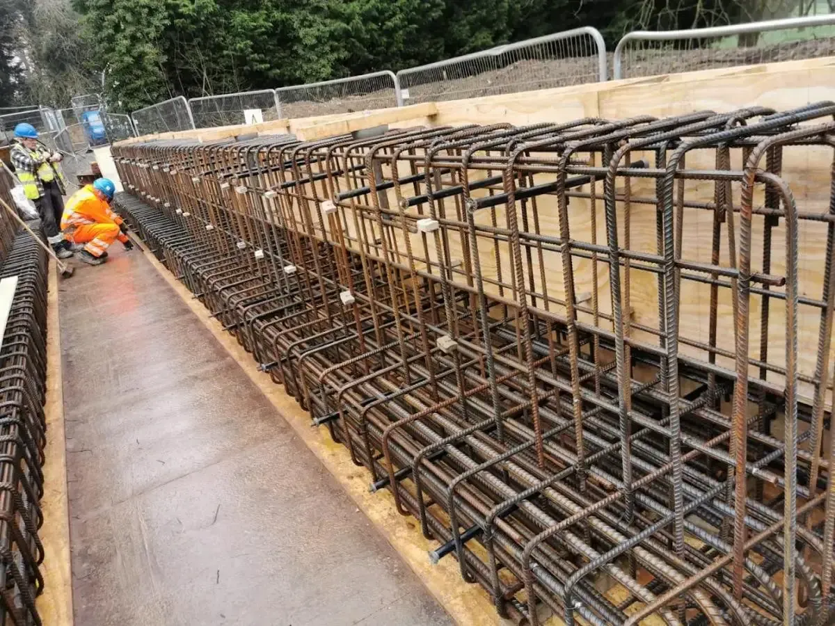 Reinforced steel framework for a construction project, with workers in safety gear.
