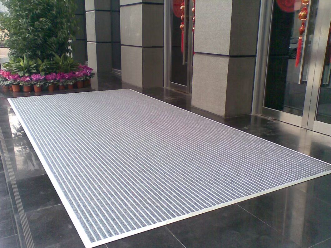 A white mat is sitting on a tiled floor in front of a building.