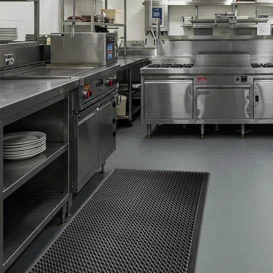 Commercial stainless-steel kitchen with counters, appliances, and black floor mats