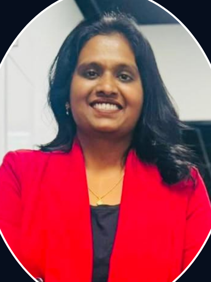Woman in red blazer smiles, indoors, chest-up view.