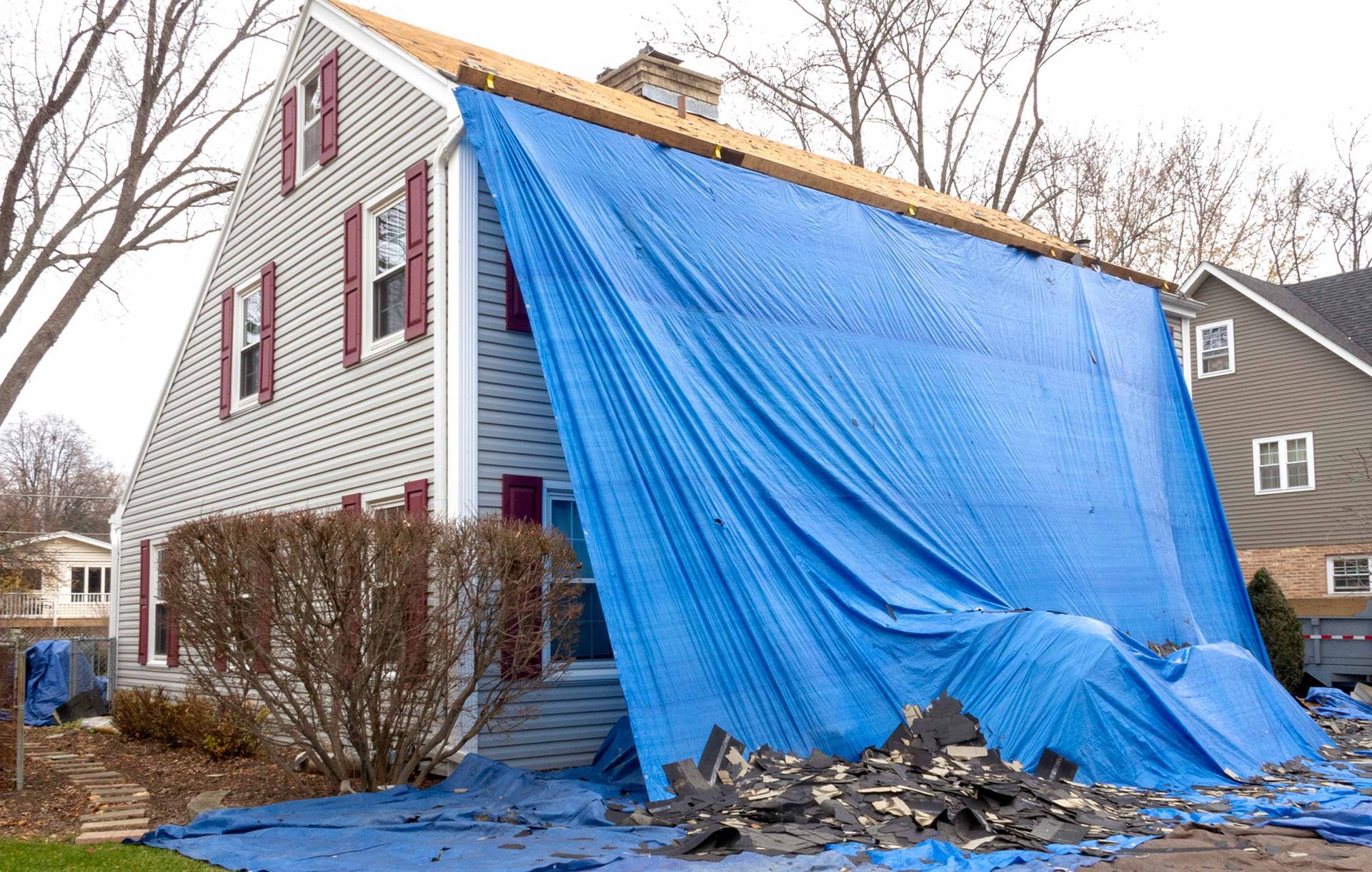 A blue tarp is covering the side of a house.