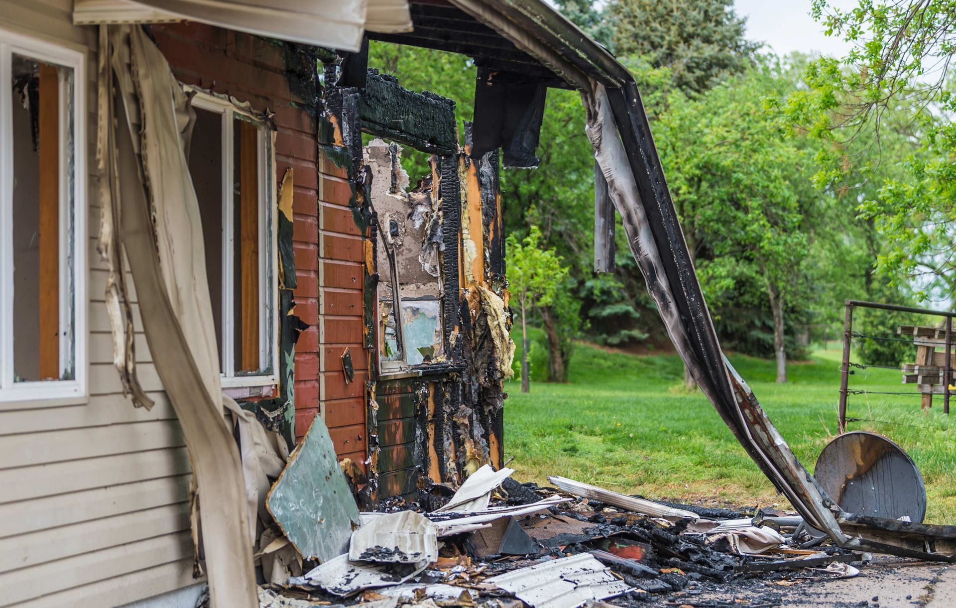 A house that has been damaged by a fire is sitting in the middle of a field.