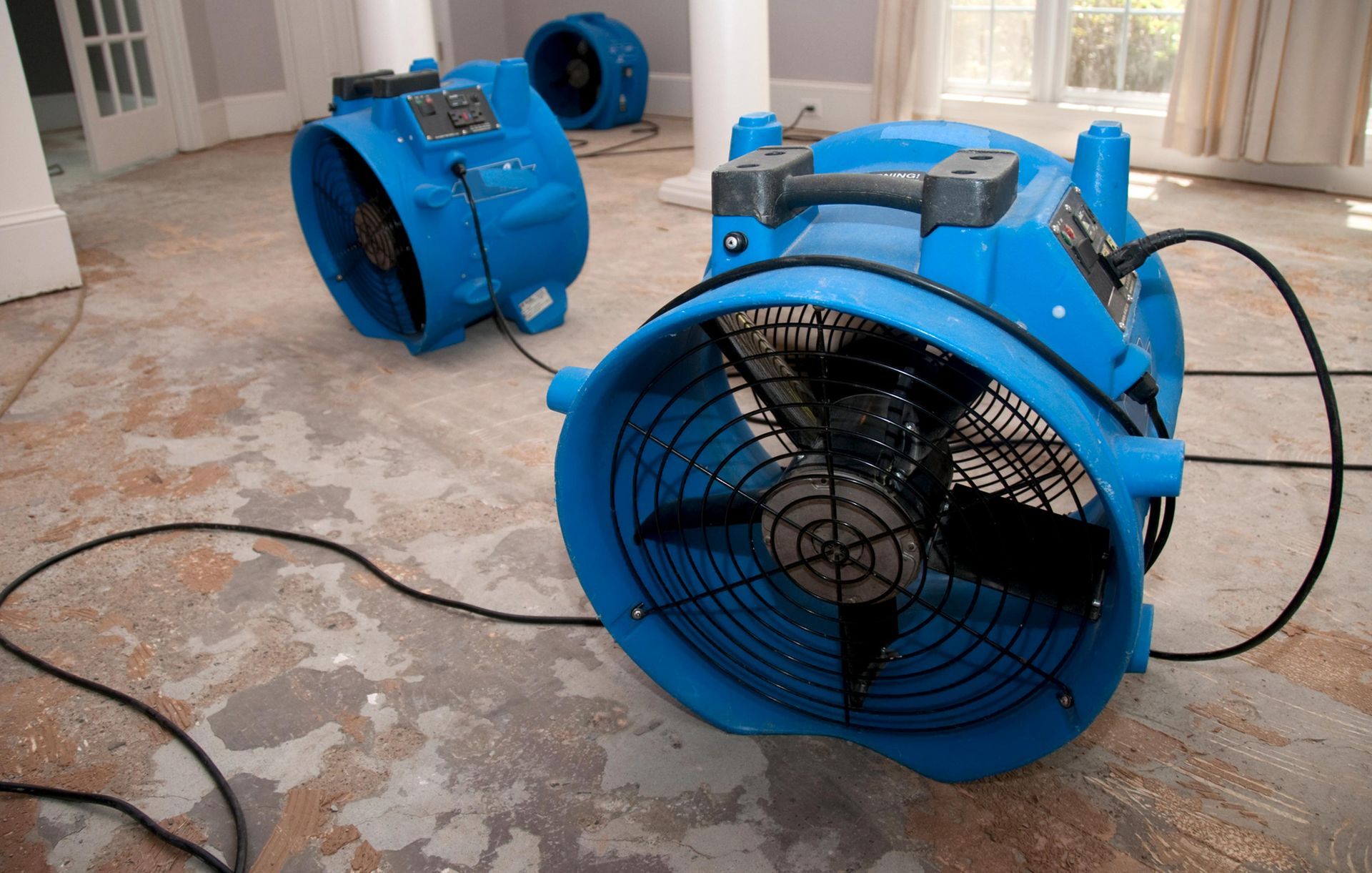 Two blue fans are sitting on the floor in a room.
