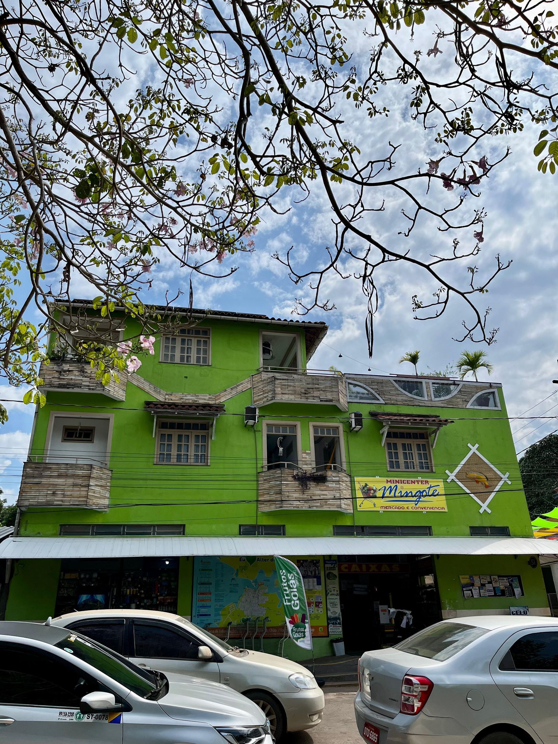 Um prédio verde com carros estacionados na frente.