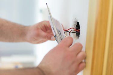 Man Installing Light Switch after Home Renovation — Electricians in Ballina