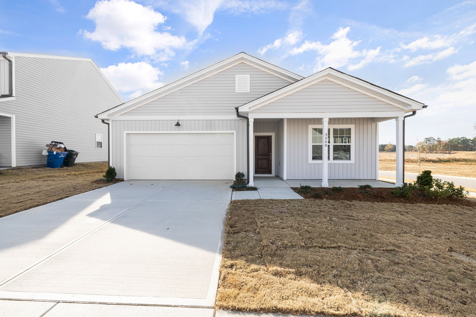 A white house with a porch and a garage is for sale.