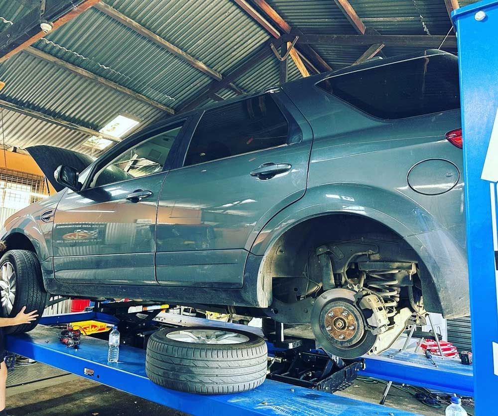 A Car Is Sitting On Top Of A Blue Lift In A Garage — Licensed Mechanic in Albury, NSW