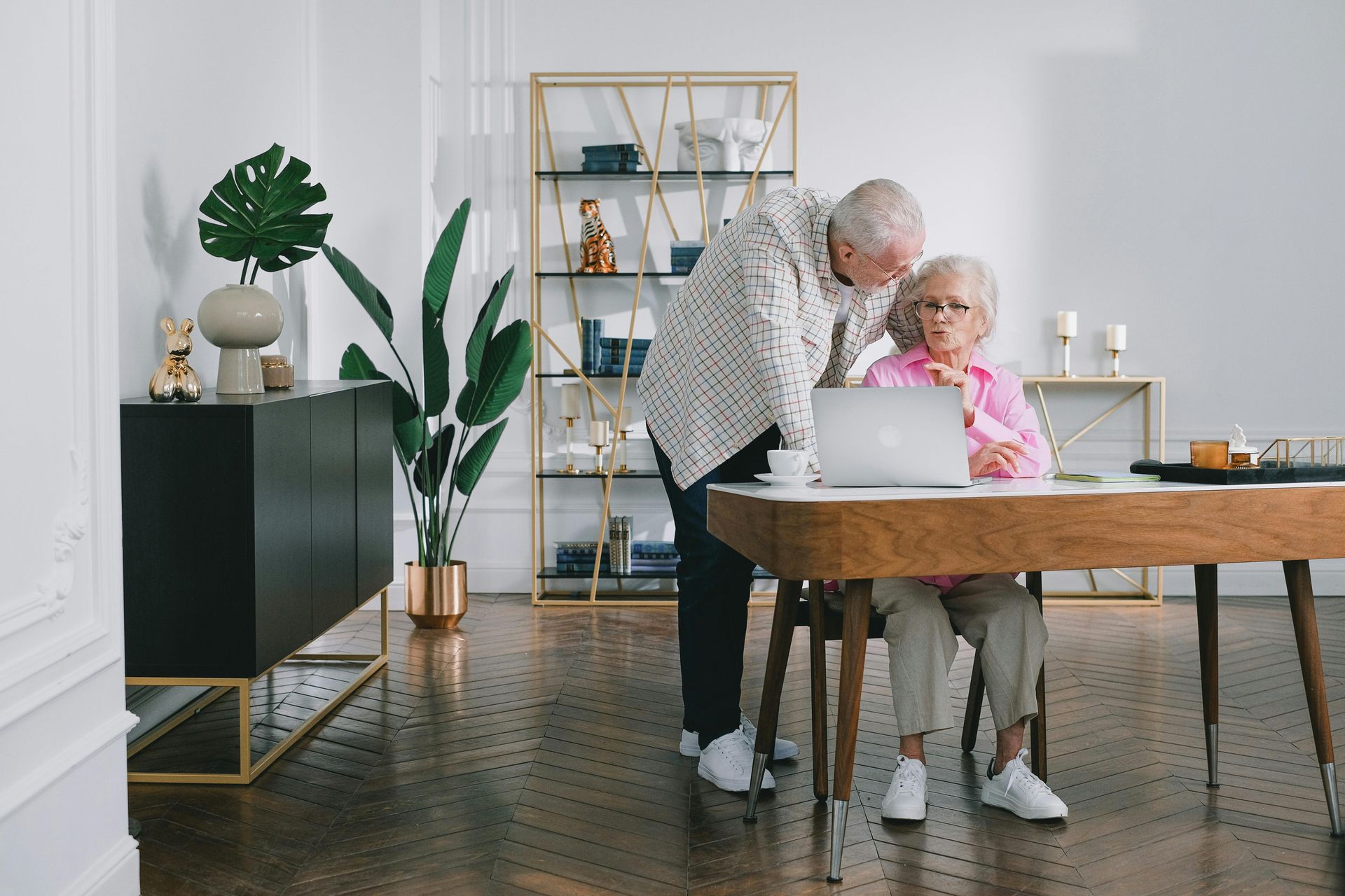 Elderly couple at a dining table with a laptop in a bright modern room