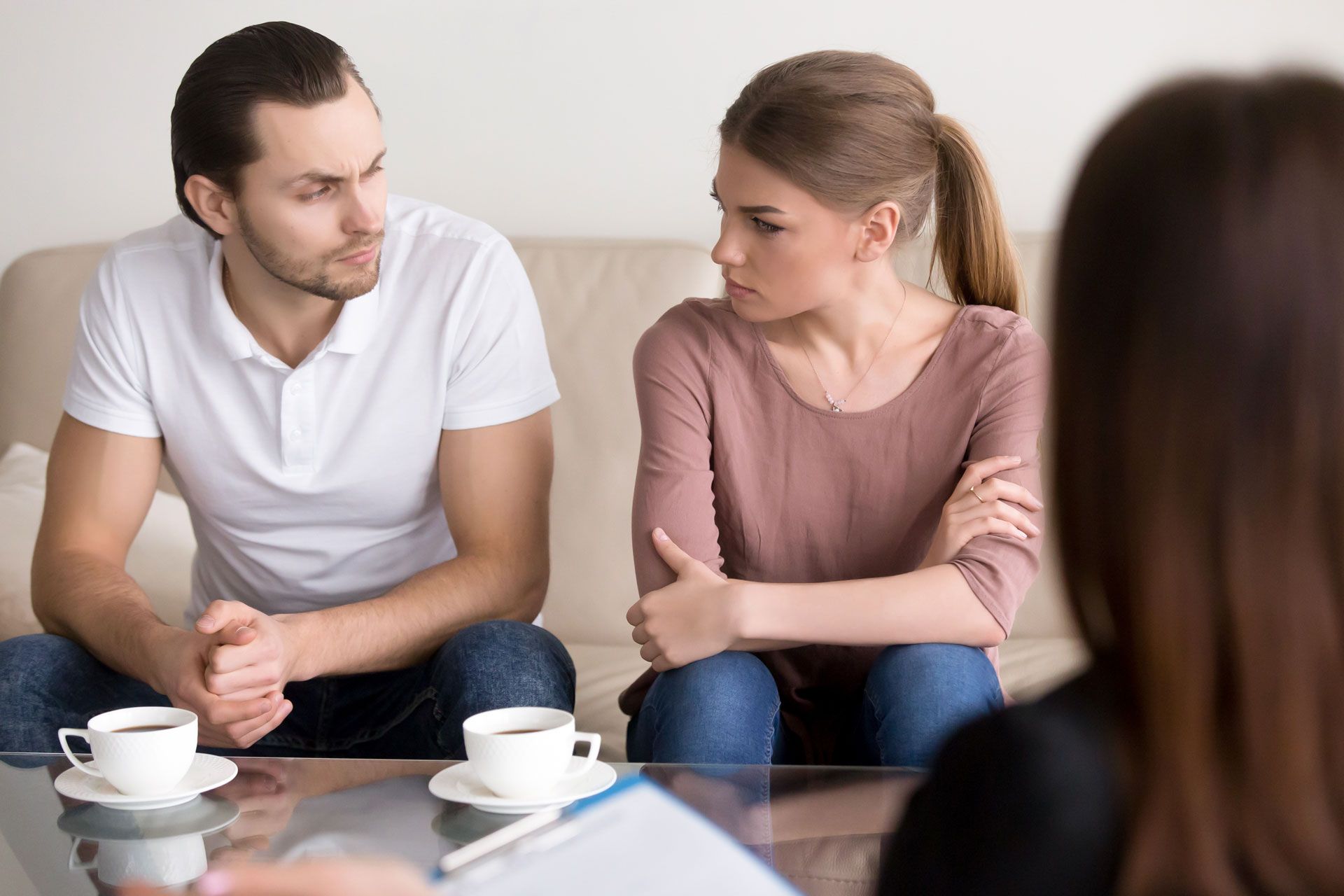 Two people talking at a café table with coffee cups, one leaning in attentively