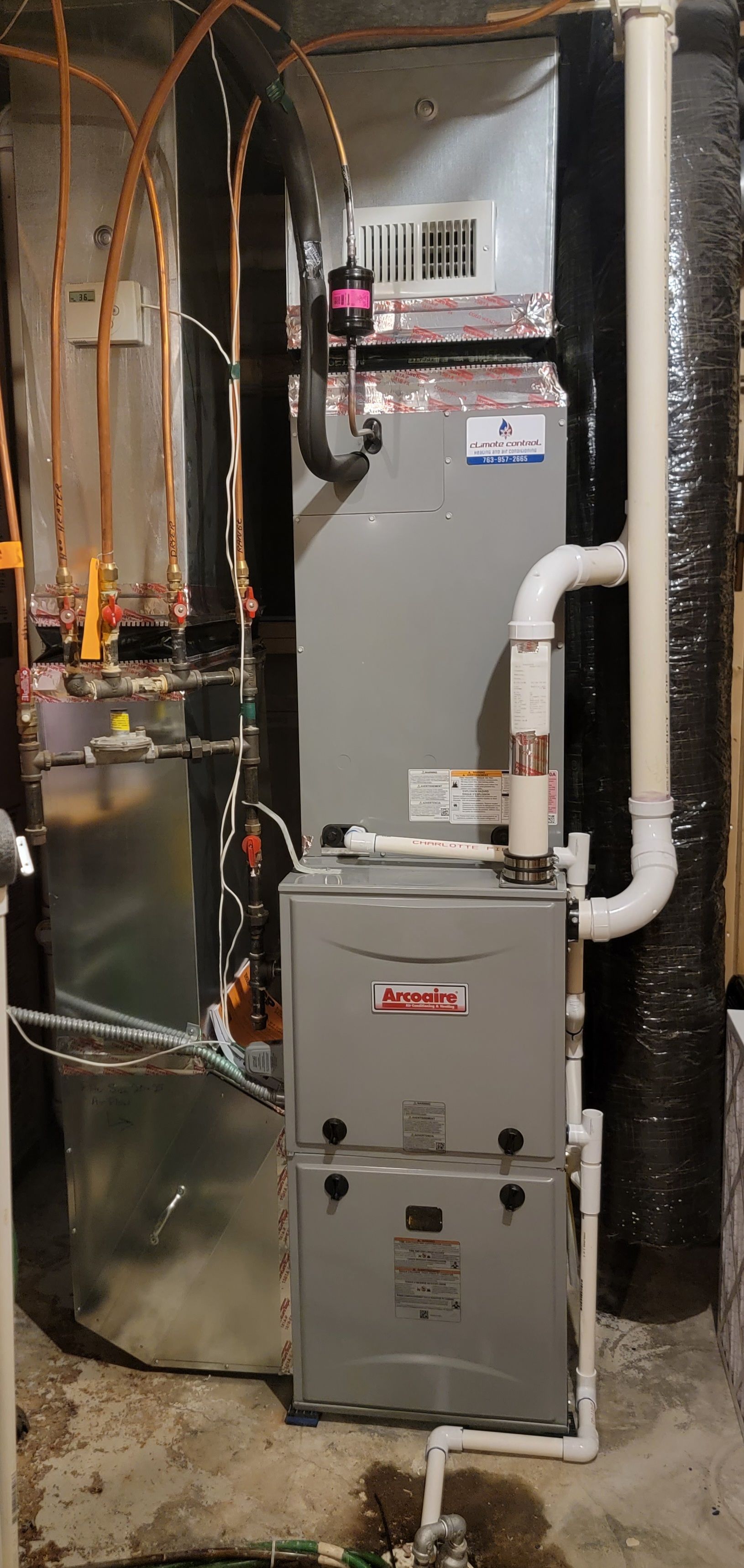 A Lennox furnace in a basement with copper pipes and ductwork.