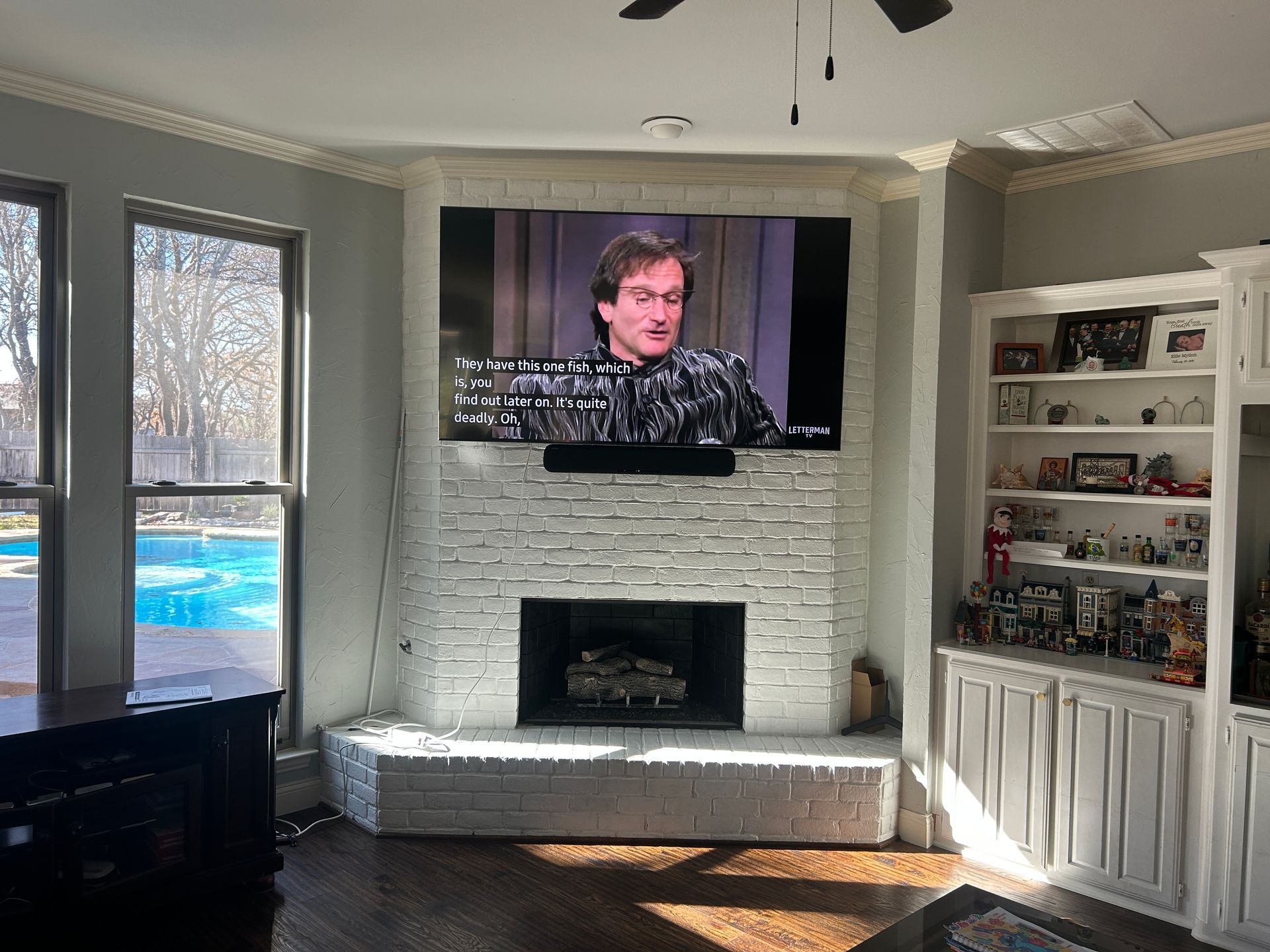 A living room with a fireplace and a flat screen tv on the wall.