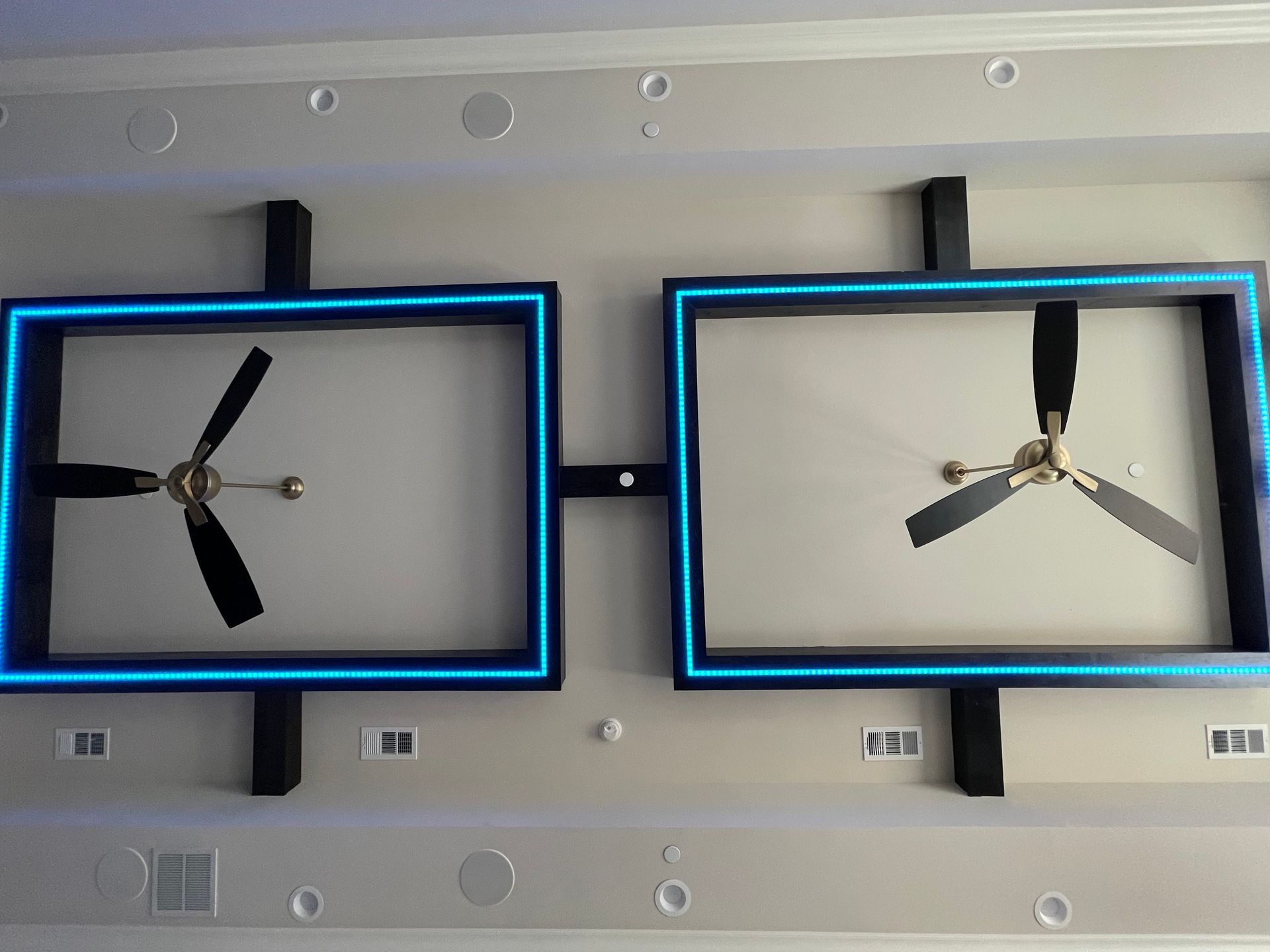 Two clocks are hanging on a wall with blue lights around them