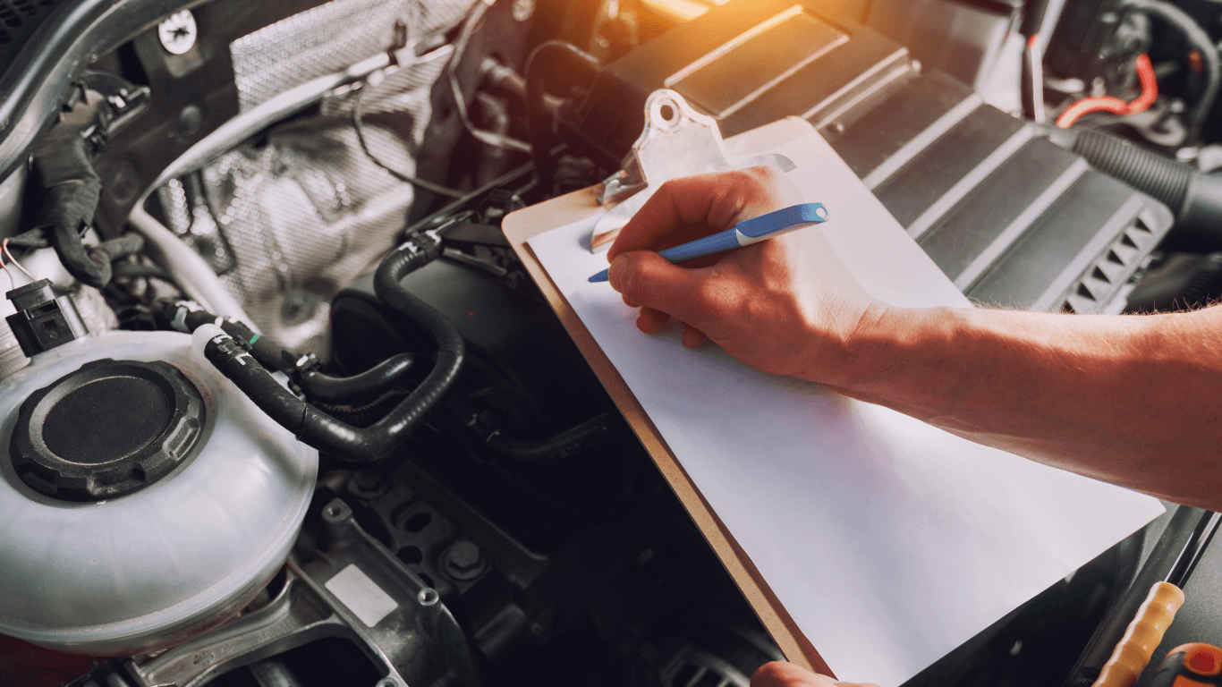 a mechanic writing on a clipboard during a pre-purchase inspection