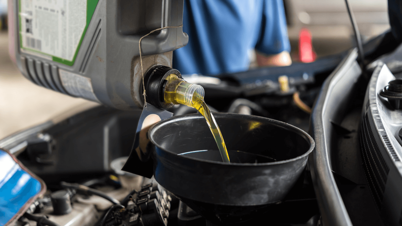 a mechanic pouring oil into a vehicle