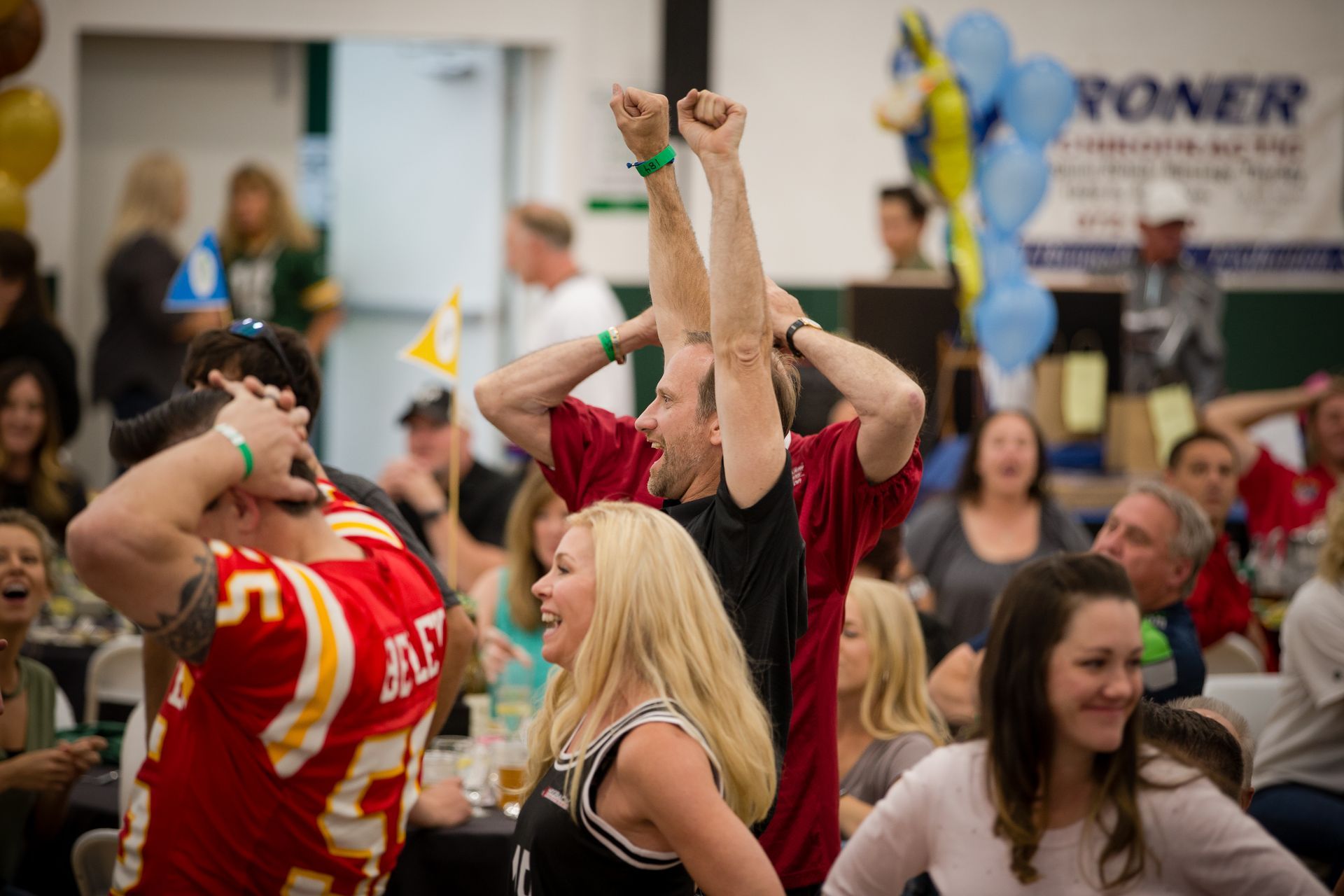 A group of people are standing in a gym with their arms in the air.