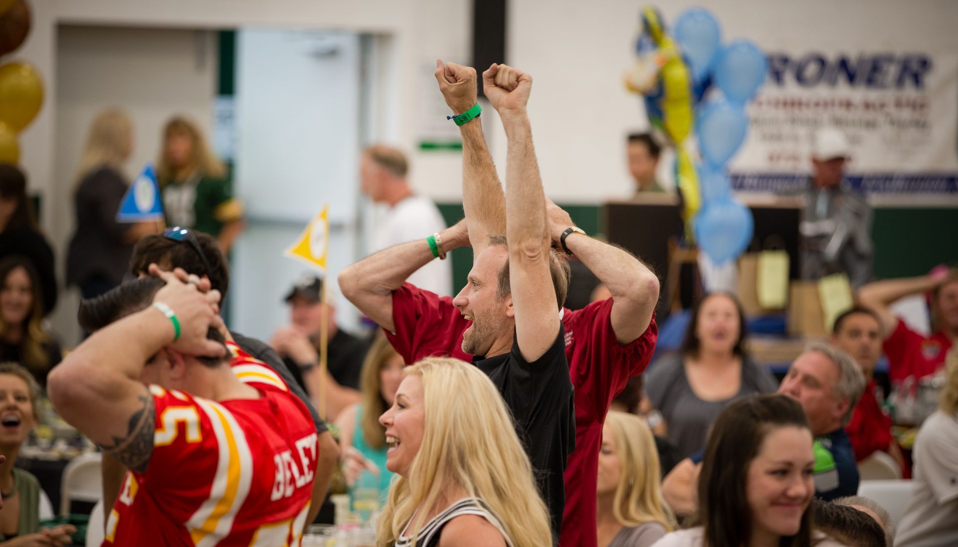 A group of people are sitting in a room with their arms in the air.