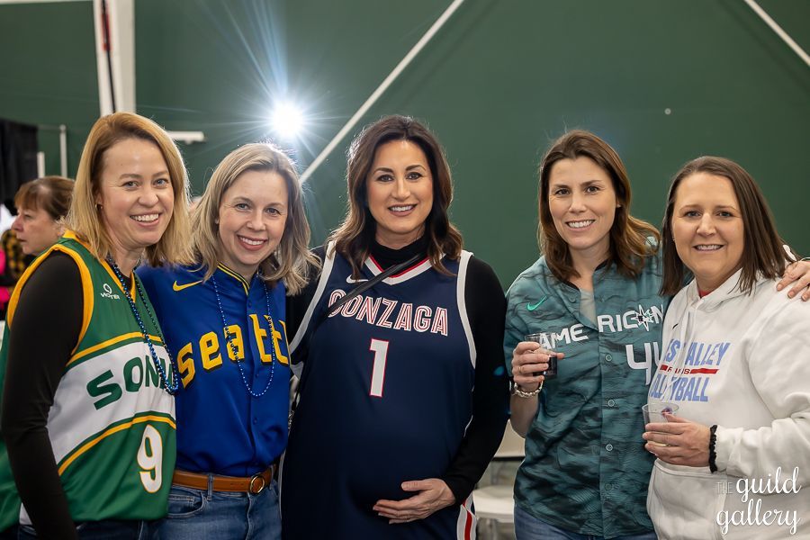 A group of women wearing basketball jerseys are posing for a picture.