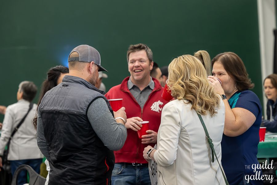 A group of people are standing in a room talking to each other.