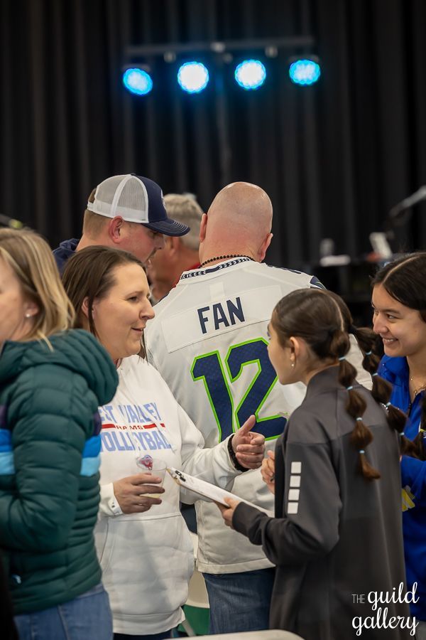 A group of people are standing around talking to each other in a room.