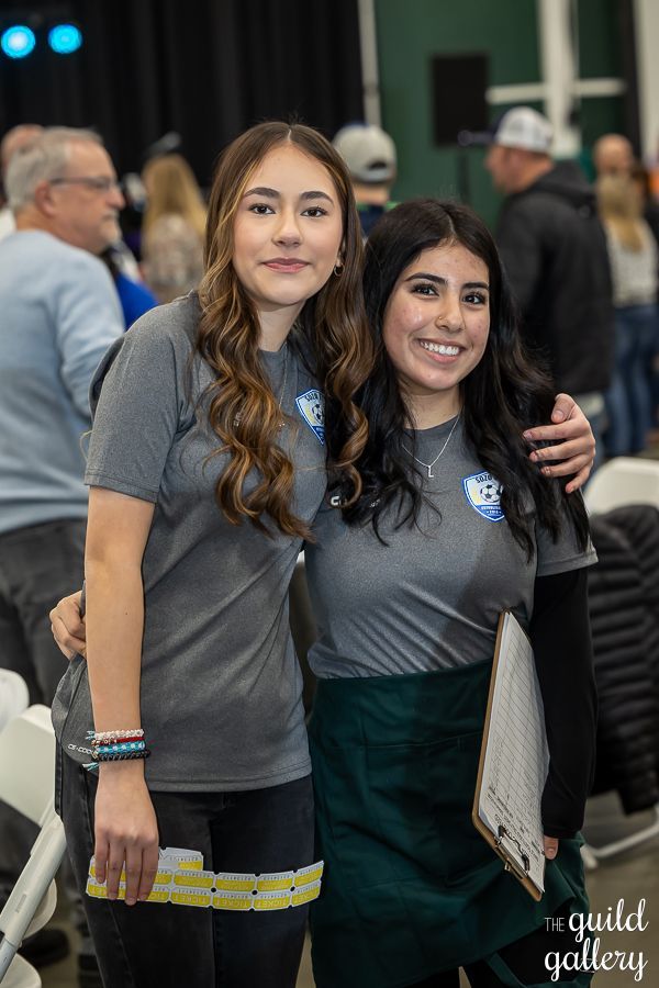 Two women are posing for a picture together at a convention.