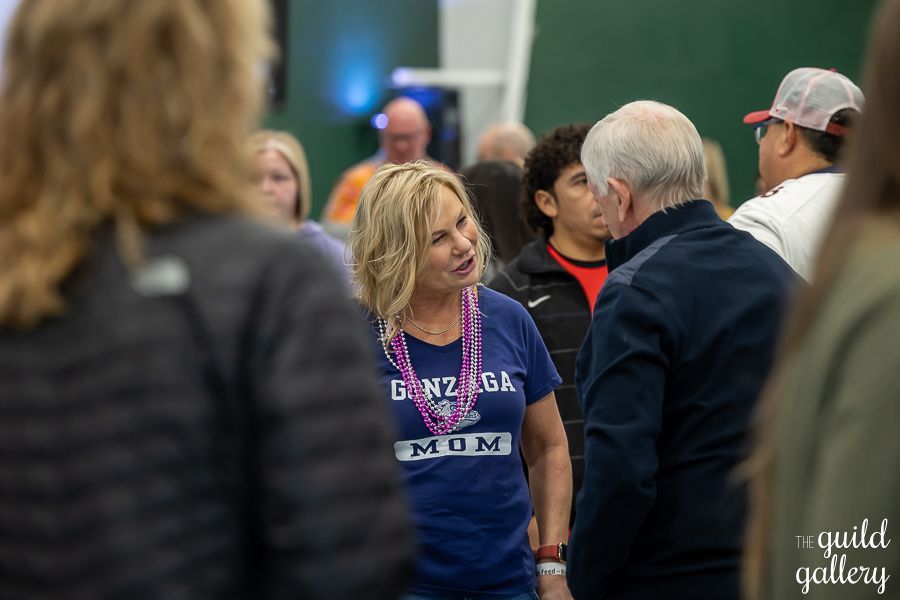 A woman in a blue shirt is talking to a man in a crowd of people.