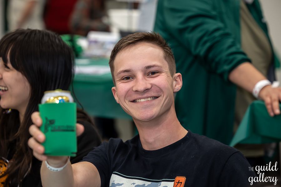 A man is holding a can of beer in a green holder.