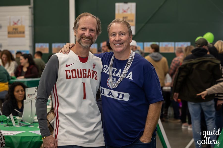 Two men are posing for a picture together at a party . one of the men is wearing a cougars jersey.