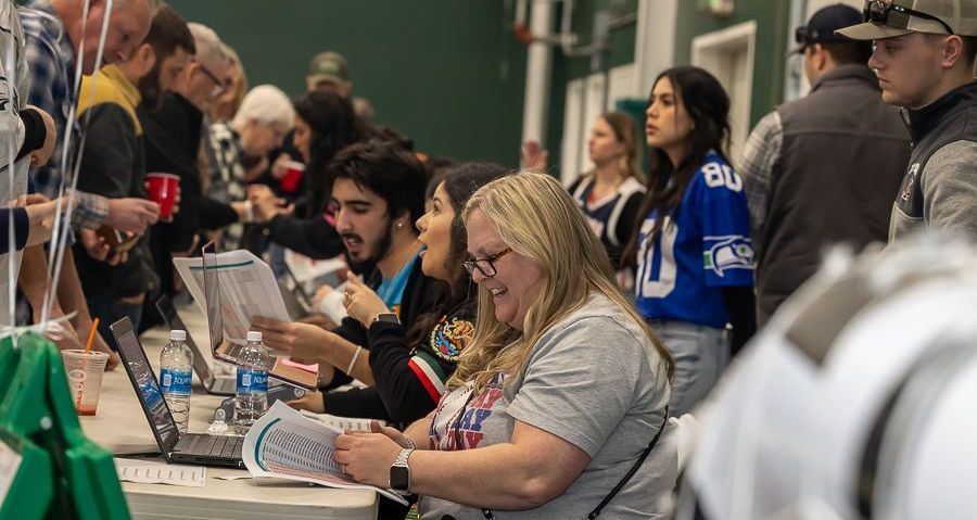 A group of people are sitting at tables with laptops.