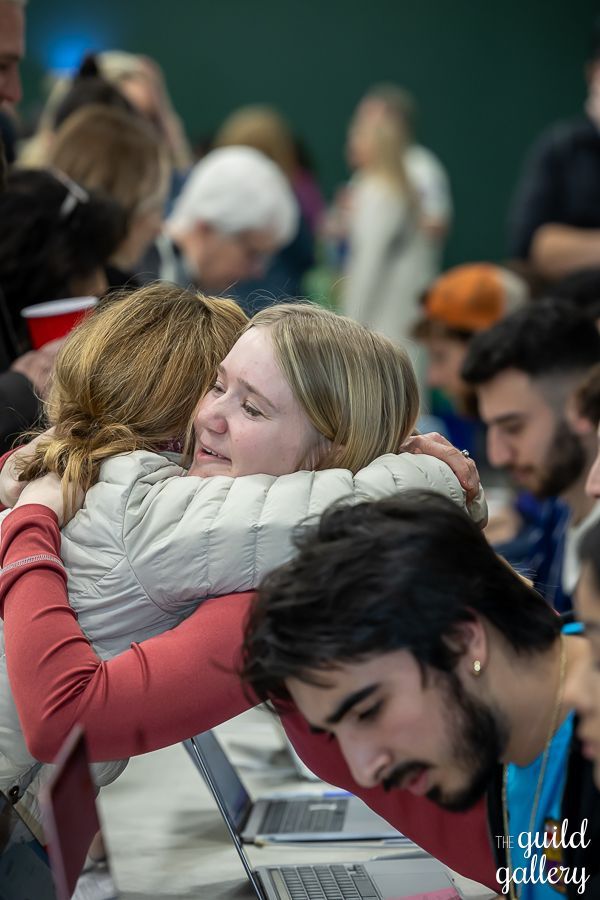 A group of people are hugging each other in a room.