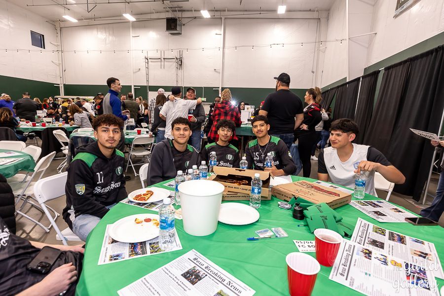 A group of young men are sitting at a table eating pizza.
