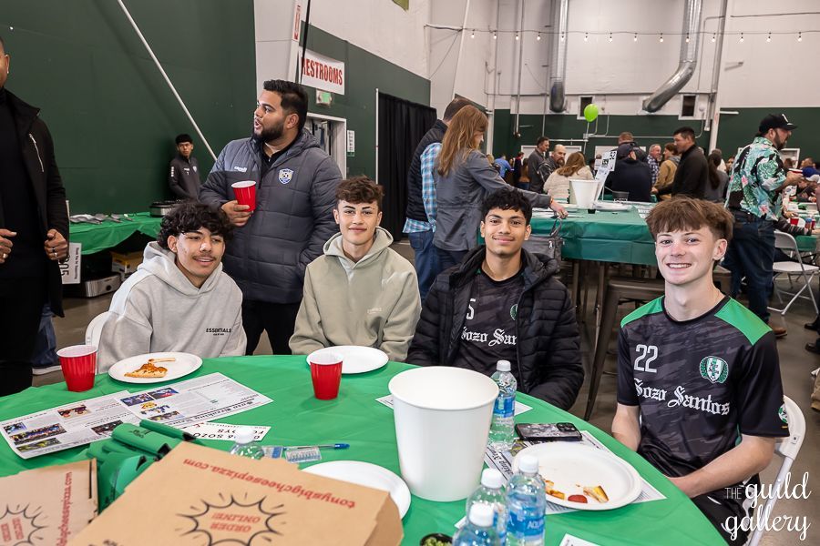 A group of young men are sitting at a table eating pizza.