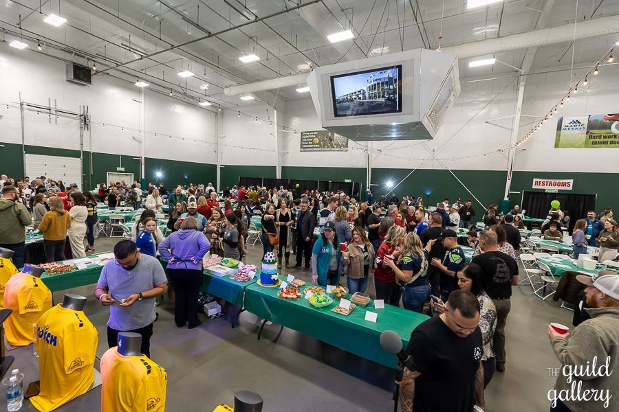 A large group of people are standing around tables in a large room.