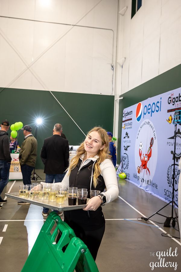 A woman is holding a tray of drinks in front of a pepsi wall.