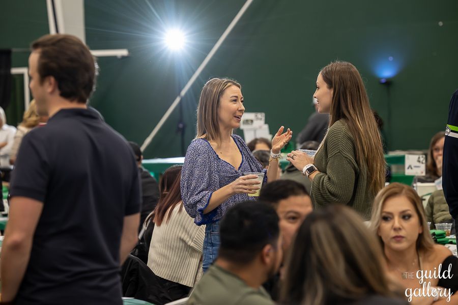 A group of people are standing in a room talking to each other.