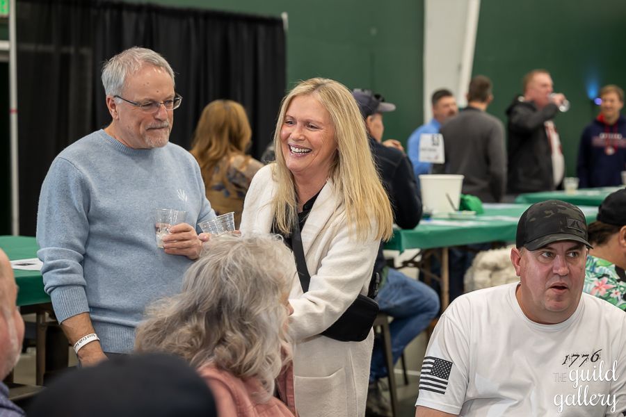 A group of people are standing around tables talking to each other.