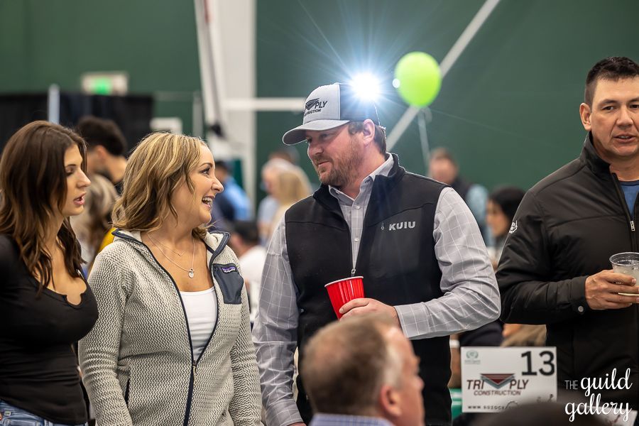 A group of people are standing in a room talking to each other.