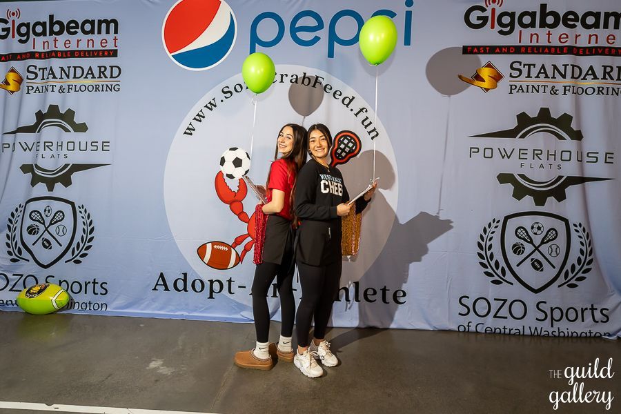 Two women standing in front of a pepsi banner