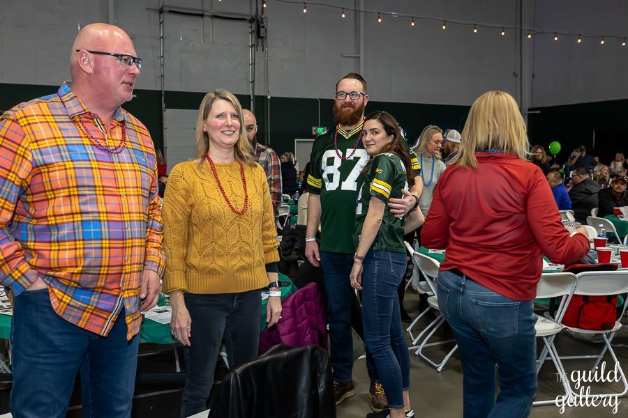A group of people are standing in a room talking to each other.