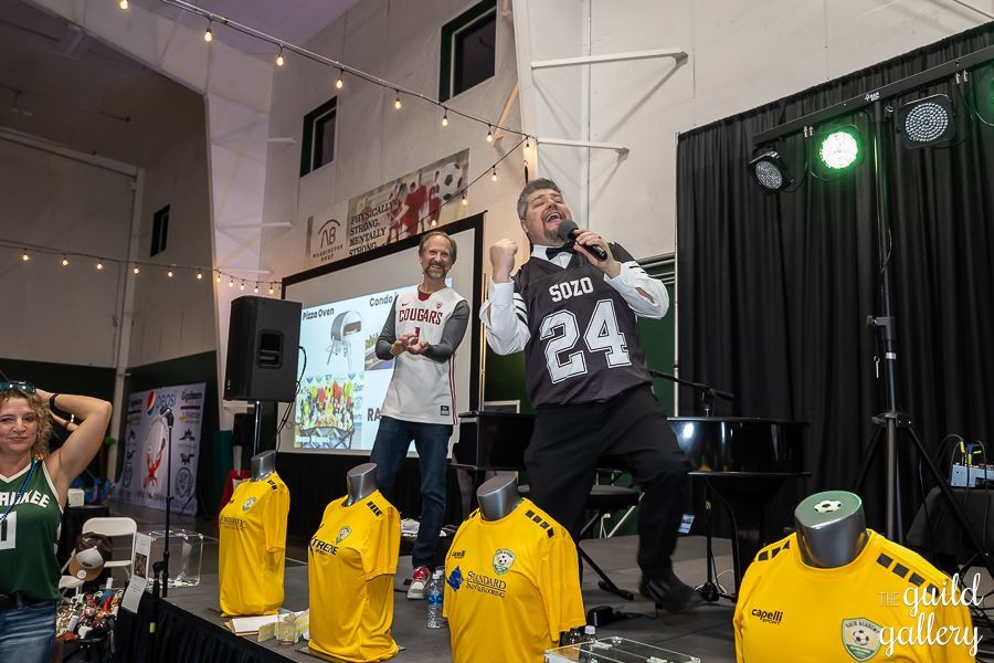 A man in a number 24 jersey is singing into a microphone on a stage.