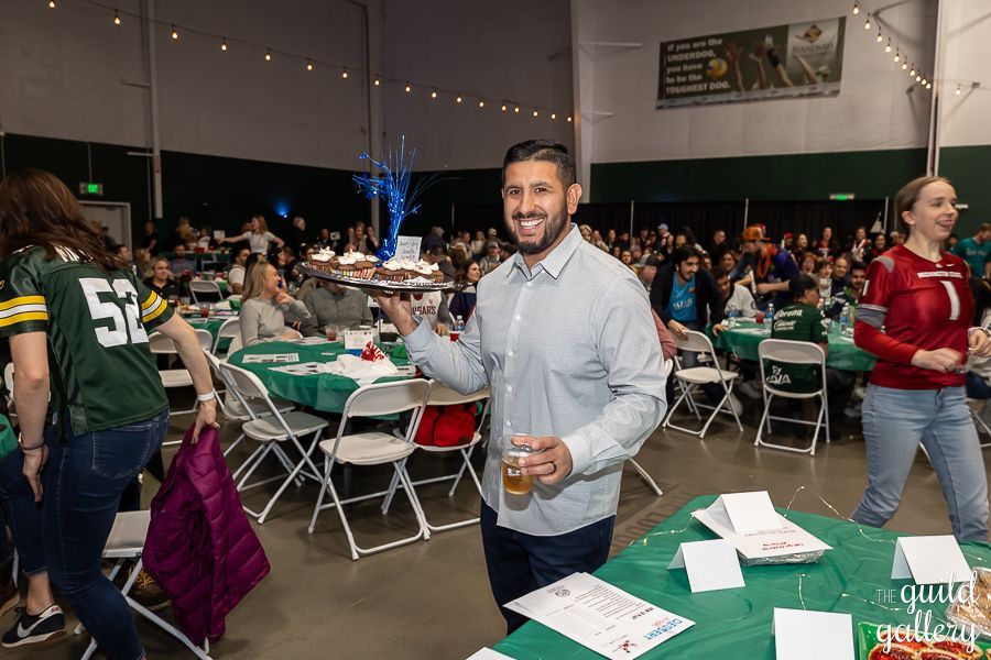 A man is standing in a crowded room holding a glass of beer.
